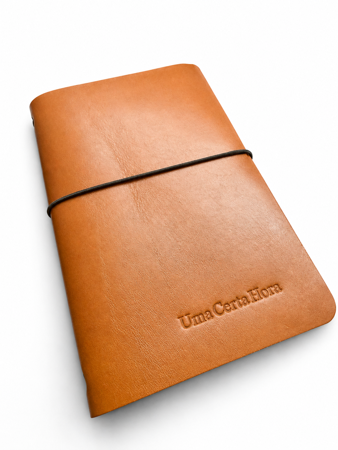 Caderno artesanal em couro genuíno castanho, capa reutilizável com elástico e gravação personalizada, fotografado em ambiente minimalista com luz natural.